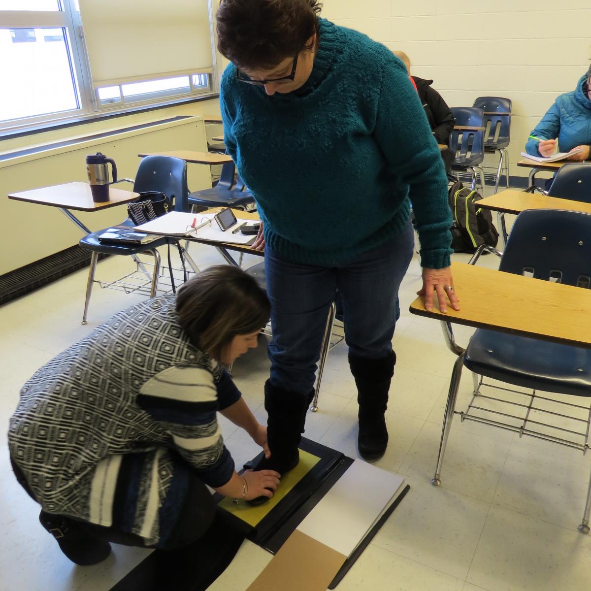 Students in a forensic nursing class make boot prints as evidence samples.