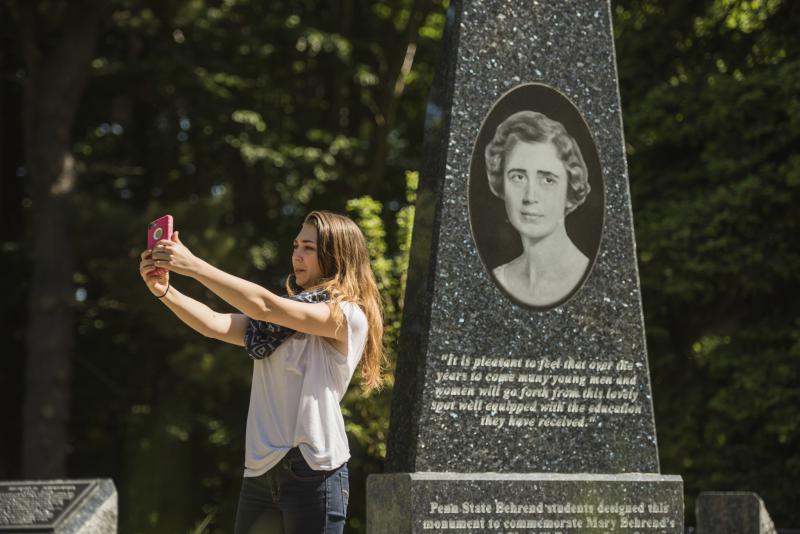 Student taking picture in front of the Mary Behrend Monument.
