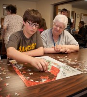 Benjamin Reinke and volunteer Martha Silka work on a jigsaw puzzle at the Union City School District. A Penn State Behrend outreach effort has reduced truancy, teen pregnancy and dropout rates in the school.