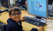 A student sits at a computer, where he has created a video game.